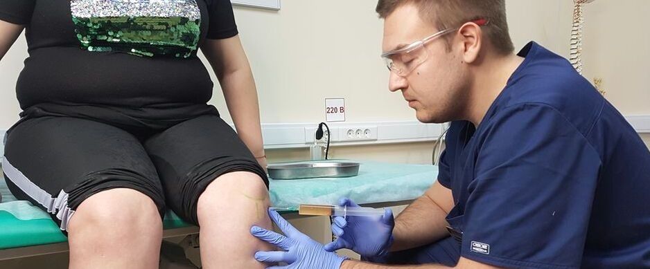 An orthopedic doctor performs an intra-articular injection in the knee joint for osteoarthritis