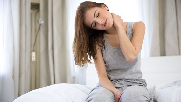 A woman feels a sharp pain in the back of her neck.
